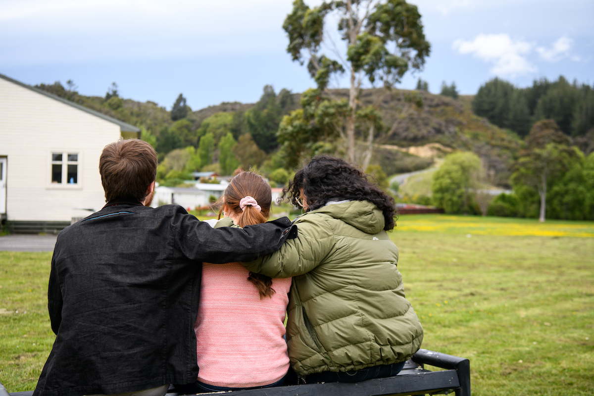 Group of friends sitting together outdoors, comforting one another, symbolising support in dealing with family violence