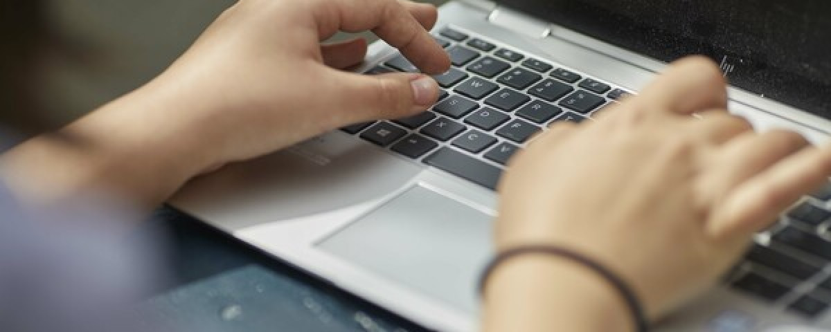 Hands of a person using a laptop to access online tools for checking relationship safety