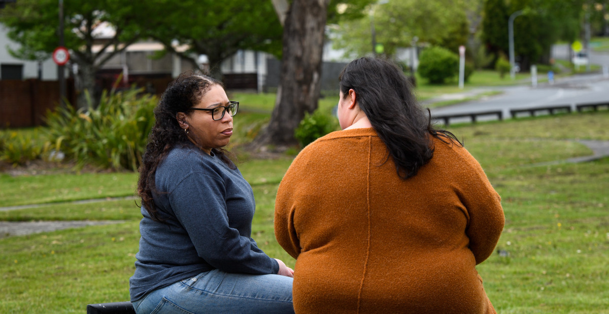 Two women engaged in a supportive conversation outdoors, symbolising getting support for family violence issues