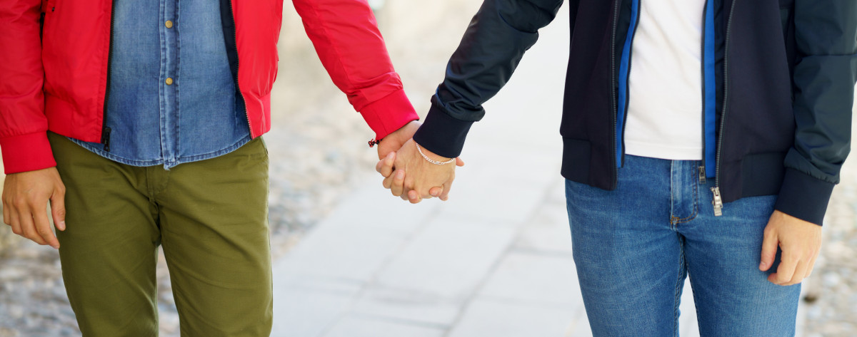 Close-up of two people holding hands together, signifying unity and support among the LGBTQIA+ community