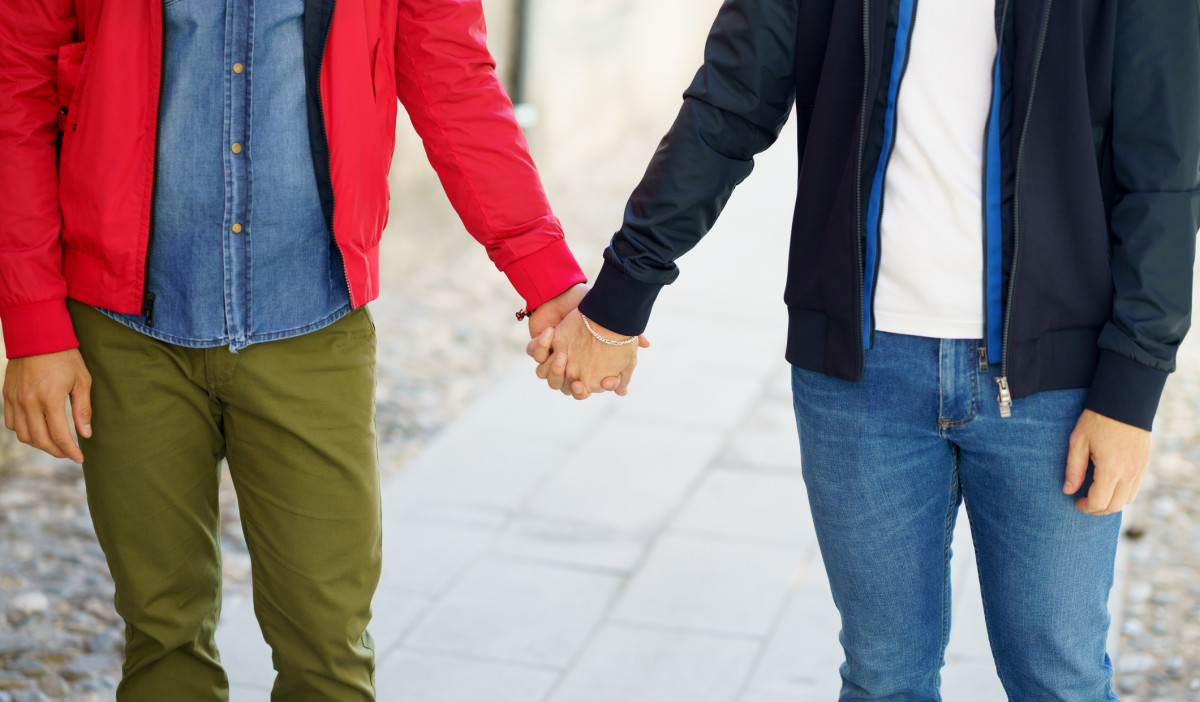 Close-up of two people holding hands together, signifying unity and support among the LGBTQIA+ community