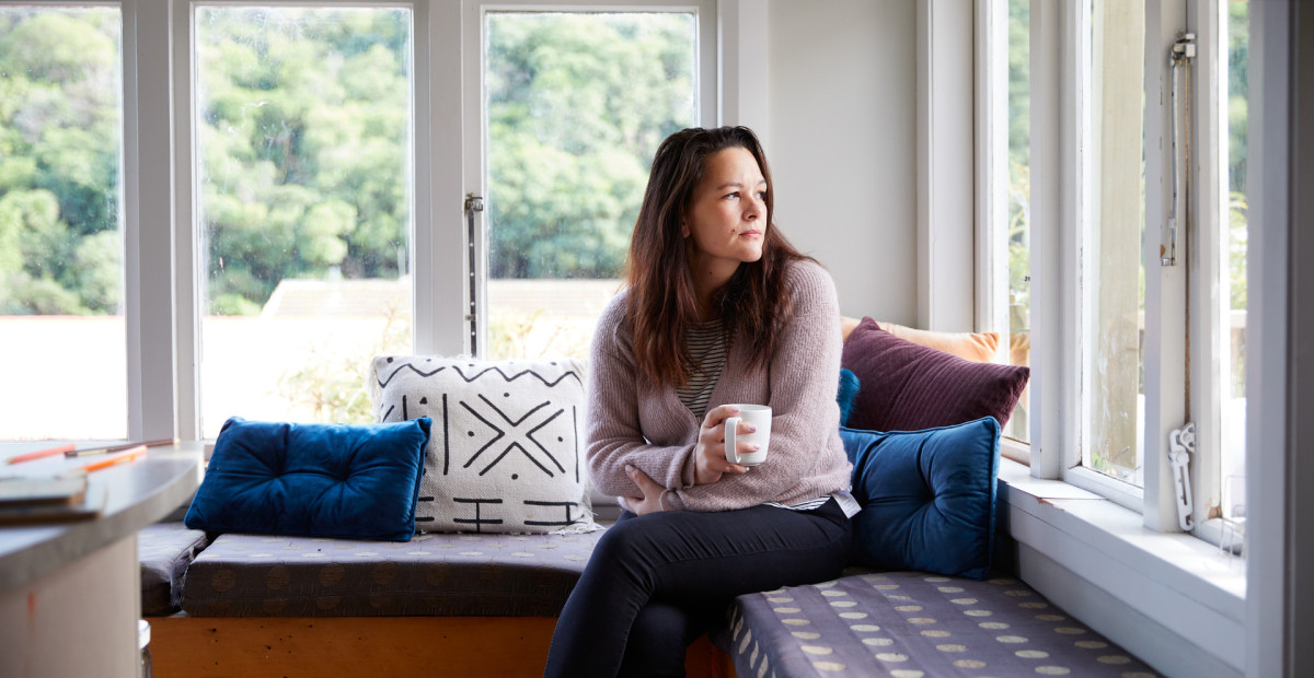 Woman looking contemplatively out the window, suggesting concern about unsafe relationship dynamics