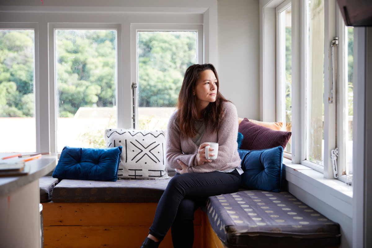 Woman looking contemplatively out the window, suggesting concern about unsafe relationship dynamics