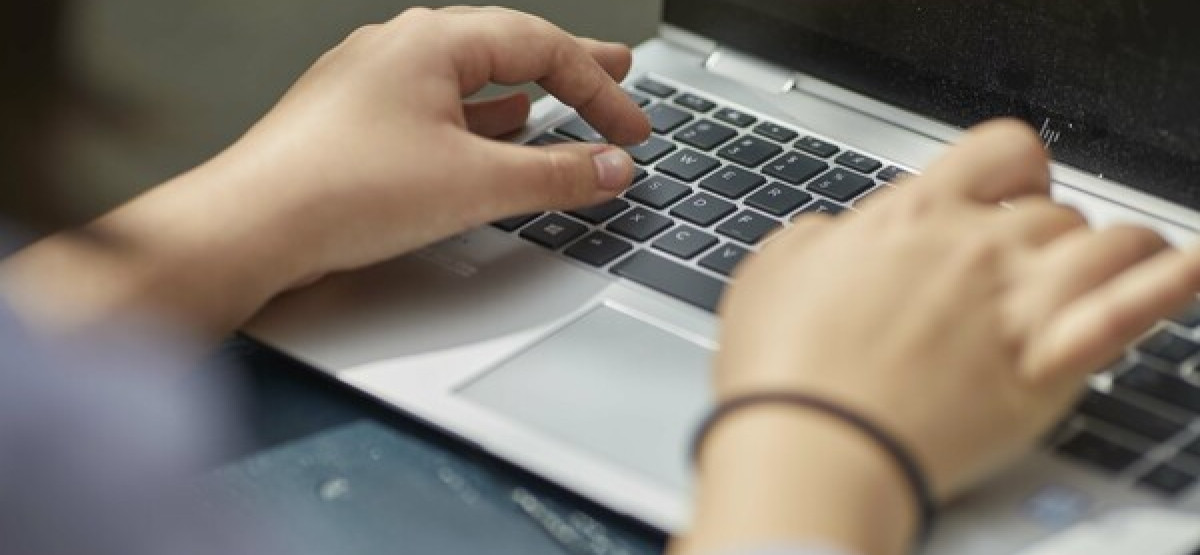 Hands of a person using a laptop to access online tools for checking relationship safety